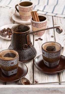 Çeşitli kahve mutfak eşyaları ve kahve çekirdekleri ile natürmort. Beyaz tahta masada.