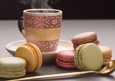 Çok renkli macaroons ve renkli Kupası, gri arka plan üzerinde atış stüdyo taze kahve.