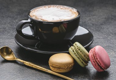 Kapuçino hatmi siyah Kupası, bademli kurabiye, koyu arka plan üzerine kaşık ile.