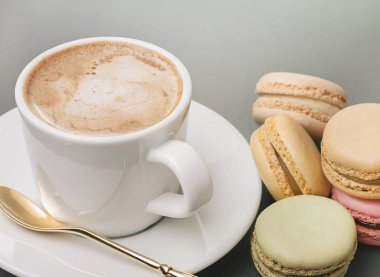 Beyaz bardak, kaşık uçan daire ve renkli taze kapuçino Fransızca macaroons. Kopya alanı.