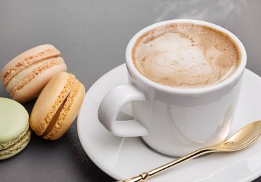 Beyaz bardak, kaşık uçan daire ve renkli taze kapuçino Fransızca macaroons. Kopya alanı.