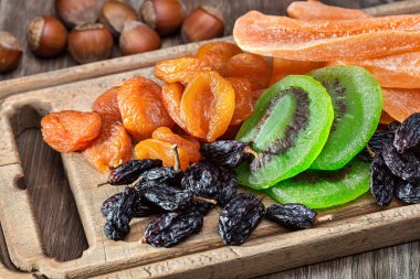 Kurutulmuş meyve ve fındık. Eski mutfak tahtası ve ahşap masa.