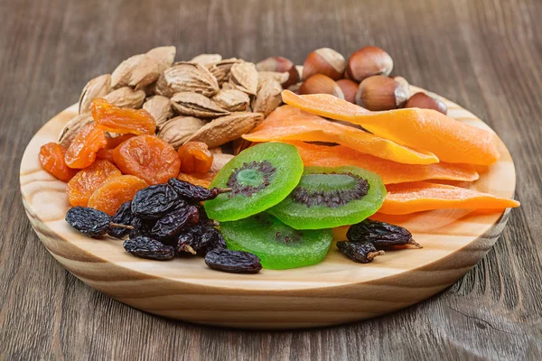 Kurutulmuş meyve ve fındık. Natürmort bir yuvarlak ahşap tahta üzerinde.