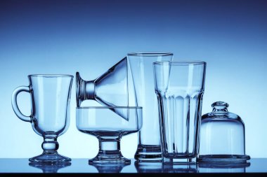  Çeşitli içecek ve yiyecek için boş cam kümesi. Yansıma yüzeyi. Çok renkli payet kokteyller için. Mavi arka plan.