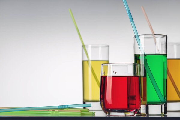 Several glasses of different multi-colored soft drinks, cocktails on white background.