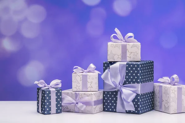 Gift boxes in smart paper with lilac ribbons, on white background. Happy Holidays. Copy space.