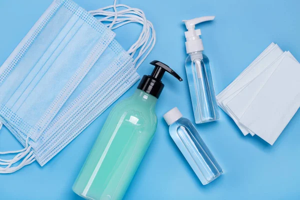 Antibacterial gel and wipes for hygiene and protection against viruses. Medical face masks. Blue background, studio shot.