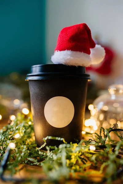 Kaffekopp med julbelysning och en hatt av Santa Claus — Stockfoto