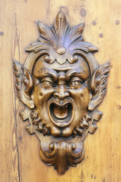 Cara demoníaca esculpida em uma porta de madeira — Fotografia de Stock