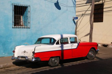 Camagüey, Cuba - 7 Mart 2018: Kırmızı ve beyaz mavi bina önünde klasik otomobil