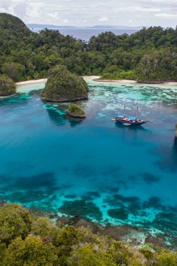 Rugged limestone islands surround a beautiful, tropical lagoon in Raja Ampat, Indonesia. This remote region is called the 