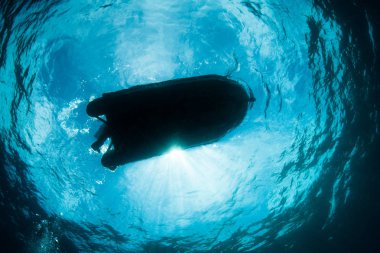 Güneş ışığı Raja Ampat içinde küçük bir tekne siluetleri. Bu tropikal bölge deniz biyoçeşitliliği nedeniyle Mercan Üçgeni kalbinde olarak bilinir.