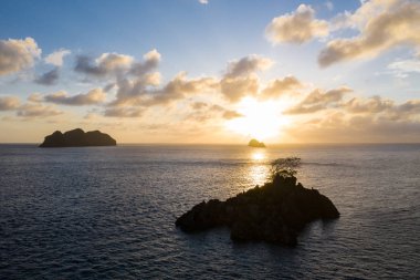 Güneş Endonezya 'nın Raja Ampat kentindeki sakin deniz manzarasının üzerinde batar. Bu bölge olağanüstü deniz biyolojik çeşitliliğine ev sahipliği yapmasıyla bilinir ve popüler bir dalış ve şnorkelle yüzme merkezidir..