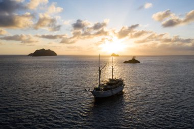Güneş Endonezya 'nın Raja Ampat kentindeki sakin deniz manzarasının üzerinde batar. Bu bölge olağanüstü deniz biyolojik çeşitliliğine ev sahipliği yapmasıyla bilinir ve popüler bir dalış ve şnorkelle yüzme merkezidir..