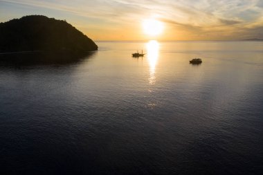 Gündoğumu, Endonezya 'nın Raja Ampat kentinin cam sularında dinlenen küçük gemileri gölgede bırakıyor. Bu güzel bölgenin dünyanın deniz biyolojik çeşitliliğinin merkezi olduğu düşünülüyor..