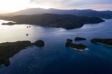 Sakin bir gündoğumu Endonezya 'nın Raja Ampat kentindeki dramatik tropikal adaları aydınlatır. Bu güzel bölgenin dünyanın deniz biyolojik çeşitliliğinin merkezi olduğu düşünülüyor..
