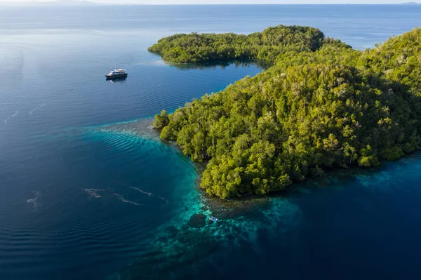A live aboard dive boat floats near a remote island in Raja Ampat, Indonesia. This region is thought to be the center of marine biodiversity and is a popular area for diving and snorkeling.