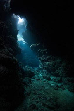 Güneş ışığı tropikal Pasifik Okyanusu 'ndaki karanlık, sualtı mağarasına sızar. Mağaralar ve mağaralar bilmece mercan resifleri ve kireçtaşı adaları.