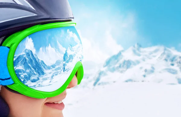 Portrait de jeune femme à la station de ski sur fond de montagnes et de ciel bleu.Une chaîne de montagnes reflétée dans le masque de ski — Photo