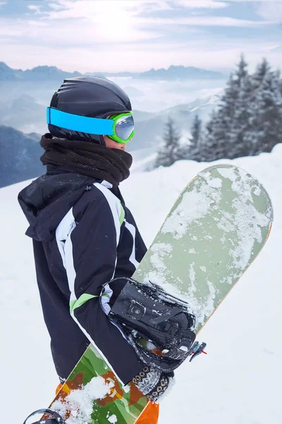 Mujer snowboarder de pie con snowboard en una mano y disfrutando del paisaje alpino de montaña. Concepto de snowboard —  Fotos de Stock