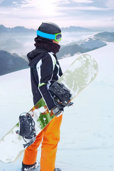 Mujer snowboarder de pie con snowboard en una mano y disfrutando del paisaje alpino de montaña. Concepto de snowboard —  Fotos de Stock