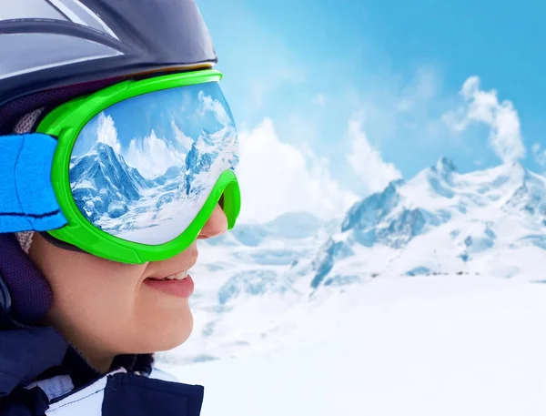 Portrait de jeune femme à la station de ski sur fond de montagnes et de ciel bleu.Une chaîne de montagnes reflétée dans le masque de ski — Photo