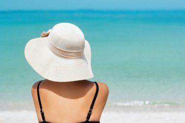 Mutlu kadın plaj tropikal mavi su tarafından yaz aylarında neşeli rahatlatıcı zevk. Güzel bikini modeli üzerinde mutlu kumsalda giyen plaj güneş şapka seyahat. Kız şapka ile tropikal bir plajda