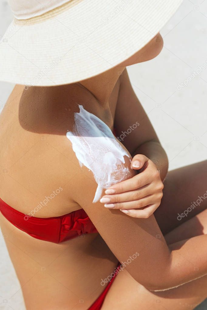 Sunscreen woman. Woman applying sunscreen on tanned skin