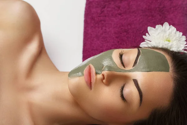 Kvinna med lera ansiktsmask i beauty spa. Hudvård. Skönhet Co — Stockfoto