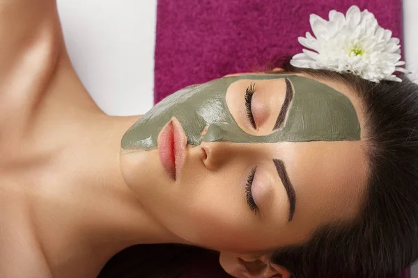 Femme avec masque facial en argile dans un spa de beauté. Soins de la peau. Concept de beauté. Gros plan portrait de belle fille avec masque facial. Traitement du visage. La cosmétologie. Soins du corps fille — Photo