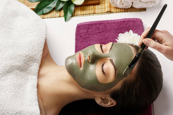 Woman with clay facial mask   in beauty spa. Skincare. Beauty Co