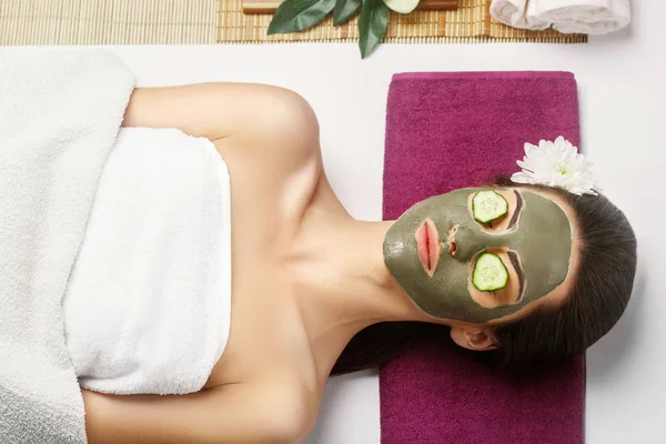 Spa Clay Mask. Woman with clay facial mask  and cucumbers on eye