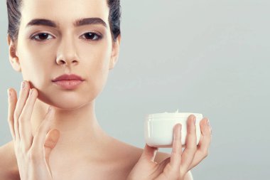 Güzel bir kadınla yüz kremi. Cilt koruma. Cilt Bakımı. Spa. Genç bir dişi nemlendirici krem tutar. Doğal makyaj
