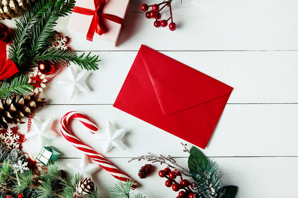 Christmas composition. Christmas gift, , pine cones, fir branches on wooden white background. Empty christmas card with envelope  Flat lay, top view, copy space. New Year.