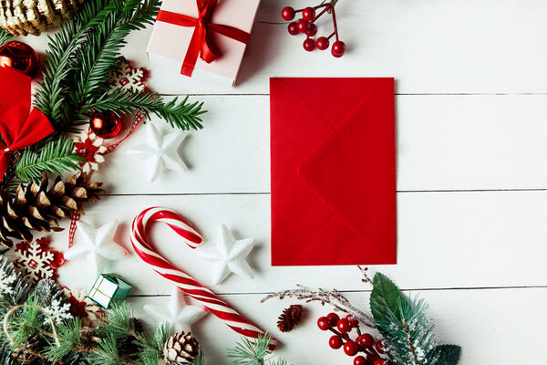 Christmas composition. Christmas gift, , pine cones, fir branches on wooden white background. Empty christmas card with envelope  Flat lay, top view, copy space. New Year.