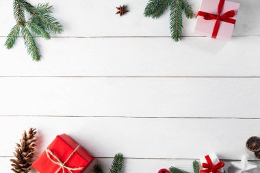 Noel hediyesi kutuları, karlı köknar dalları, kozalaklı kozalaklar, tarçınlı kurutulmuş meyveler, bayram süslemeleri, karamel çubukları olan ahşap beyaz arka planda güzel bir Noel kompozisyonu. Yeni yıl. Üst görünüm, alanı kopyala.