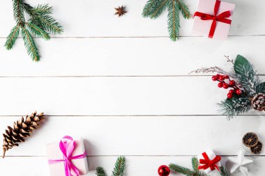 Noel hediyesi kutuları, karlı köknar dalları, kozalaklı kozalaklar, tarçınlı kurutulmuş meyveler, bayram süslemeleri, karamel çubukları olan ahşap beyaz arka planda güzel bir Noel kompozisyonu. Yeni yıl. Üst görünüm, alanı kopyala.