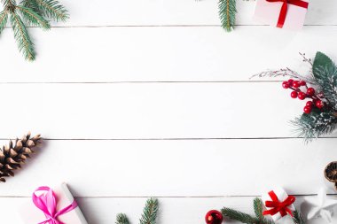 Noel hediyesi kutuları, karlı köknar dalları, kozalaklı kozalaklar, tarçınlı kurutulmuş meyveler, bayram süslemeleri, karamel çubukları olan ahşap beyaz arka planda güzel bir Noel kompozisyonu. Yeni yıl. Üst görünüm, alanı kopyala.