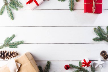 Noel hediyesi kutuları, karlı köknar dalları, kozalaklı kozalaklar, tarçınlı kurutulmuş meyveler, bayram süslemeleri, karamel çubukları olan ahşap beyaz arka planda güzel bir Noel kompozisyonu. Yeni yıl. Üst görünüm, alanı kopyala.