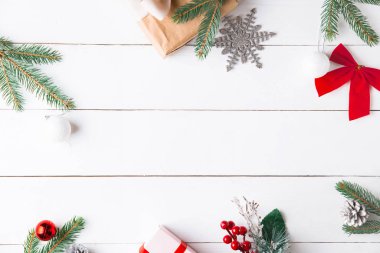 Noel hediyesi kutuları, karlı köknar dalları, kozalaklı kozalaklar, tarçınlı kurutulmuş meyveler, bayram süslemeleri, karamel çubukları olan ahşap beyaz arka planda güzel bir Noel kompozisyonu. Yeni yıl. Üst görünüm, alanı kopyala.