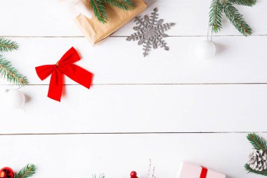 Noel hediyesi kutuları, karlı köknar dalları, kozalaklı kozalaklar, tarçınlı kurutulmuş meyveler, bayram süslemeleri, karamel çubukları olan ahşap beyaz arka planda güzel bir Noel kompozisyonu. Yeni yıl. Üst görünüm, alanı kopyala.