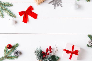 Noel hediyesi kutuları, karlı köknar dalları, kozalaklı kozalaklar, tarçınlı kurutulmuş meyveler, bayram süslemeleri, karamel çubukları olan ahşap beyaz arka planda güzel bir Noel kompozisyonu. Yeni yıl. Üst görünüm, alanı kopyala.