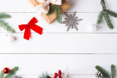 Noel hediyesi kutuları, karlı köknar dalları, kozalaklı kozalaklar, tarçınlı kurutulmuş meyveler, bayram süslemeleri, karamel çubukları olan ahşap beyaz arka planda güzel bir Noel kompozisyonu. Yeni yıl. Üst görünüm, alanı kopyala.