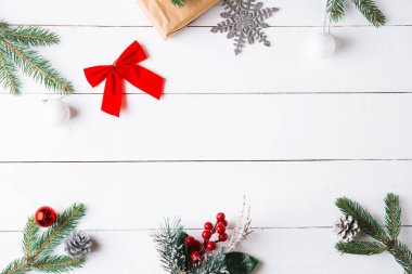 Noel hediyesi kutuları, karlı köknar dalları, kozalaklı kozalaklar, tarçınlı kurutulmuş meyveler, bayram süslemeleri, karamel çubukları olan ahşap beyaz arka planda güzel bir Noel kompozisyonu. Yeni yıl. Üst görünüm, alanı kopyala.