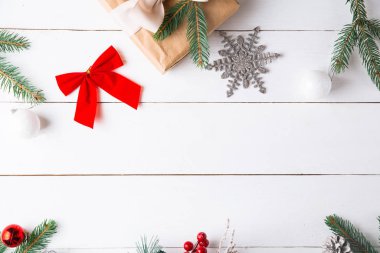 Noel hediyesi kutuları, karlı köknar dalları, kozalaklı kozalaklar, tarçınlı kurutulmuş meyveler, bayram süslemeleri, karamel çubukları olan ahşap beyaz arka planda güzel bir Noel kompozisyonu. Yeni yıl. Üst görünüm, alanı kopyala.