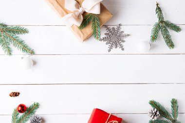 Noel hediyesi kutuları, karlı köknar dalları, kozalaklı kozalaklar, tarçınlı kurutulmuş meyveler, bayram süslemeleri, karamel çubukları olan ahşap beyaz arka planda güzel bir Noel kompozisyonu. Yeni yıl. Üst görünüm, alanı kopyala.