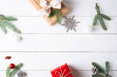 Noel hediyesi kutuları, karlı köknar dalları, kozalaklı kozalaklar, tarçınlı kurutulmuş meyveler, bayram süslemeleri, karamel çubukları olan ahşap beyaz arka planda güzel bir Noel kompozisyonu. Yeni yıl. Üst görünüm, alanı kopyala.