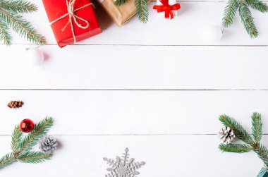 Noel hediyesi kutuları, karlı köknar dalları, kozalaklı kozalaklar, tarçınlı kurutulmuş meyveler, bayram süslemeleri, karamel çubukları olan ahşap beyaz arka planda güzel bir Noel kompozisyonu. Yeni yıl. Üst görünüm, alanı kopyala.