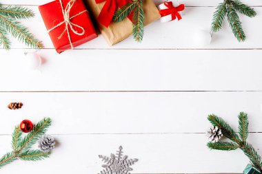 Noel hediyesi kutuları, karlı köknar dalları, kozalaklı kozalaklar, tarçınlı kurutulmuş meyveler, bayram süslemeleri, karamel çubukları olan ahşap beyaz arka planda güzel bir Noel kompozisyonu. Yeni yıl. Üst görünüm, alanı kopyala.