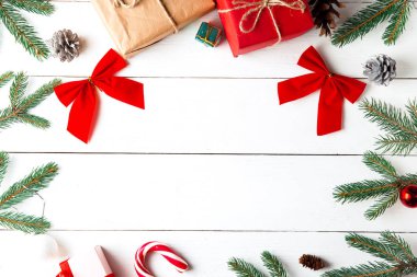 Ahşap beyaz arka planda güzel bir Noel kompozisyonu. Noel hediye kutuları, karlı köknar dalları, kozalaklı kozalaklar, karamel çubuğu, hediye. Yeni yıl. Üst görünüm, alanı kopyala.